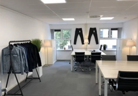Modern kantoor aan de Arlandaweg met werkplekken, denim kledingrek en opgehangen spijkerbroeken aan de muur.
