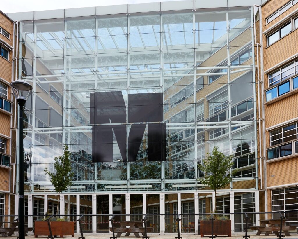 Glazen gevel van het Media Park-gebouw met groot zwart M-logo in het midden.