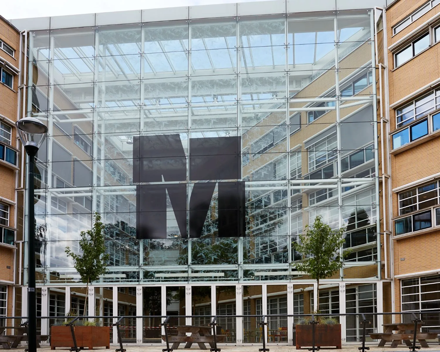 Glazen gevel van het Media Park-gebouw met groot zwart M-logo in het midden.