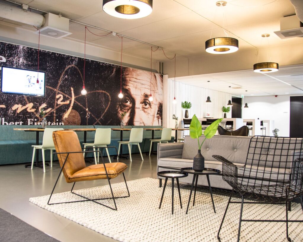 Moderne lounge- en werkruimte met een muurschildering van Albert Einstein op de achtergrond.