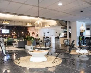 Moderne lounge- en zitruimte met zwarte stoelen, ronde tafels en een muurschildering van Albert Einstein op de achtergrond.