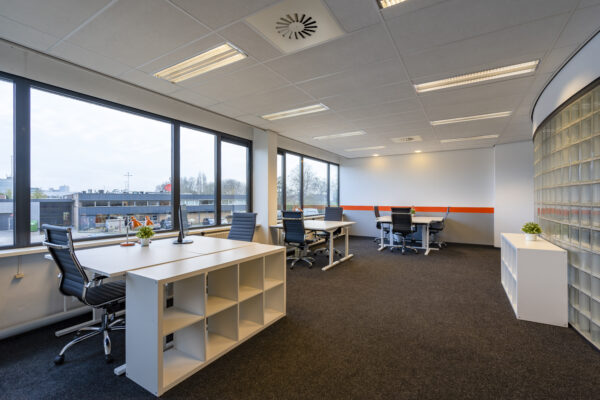 Modern kantoorinterieur in Aalsmeer met grote ramen, bureaus, en ergonomische stoelen.