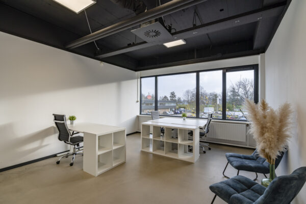 Moderne kantoorruimte in de Aalsmeer studio met strakke witte bureaus, ergonomische stoelen en grote ramen met uitzicht.