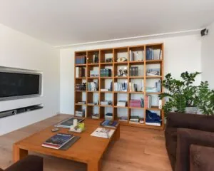 Modern ingerichte woonkamer met houten boekenkast, lage salontafel en ingebouwde tv aan de Dr. Lelykade 257 in Den Haag.