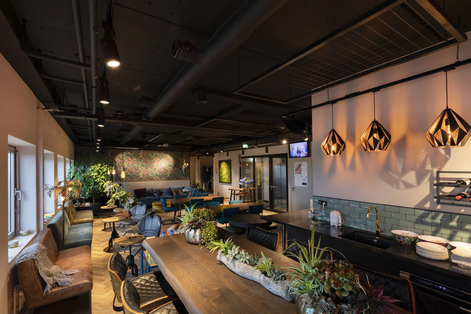 Gezellige pantry foyer van de Academie met planten, zithoeken en warme verlichting.