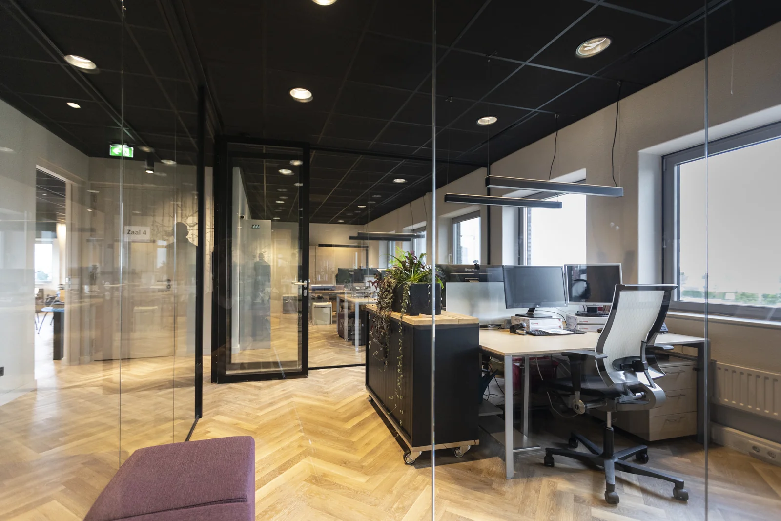 Moderne kantoorruimte in de Academie met glazen wanden, werkplekken en uitzicht naar buiten.