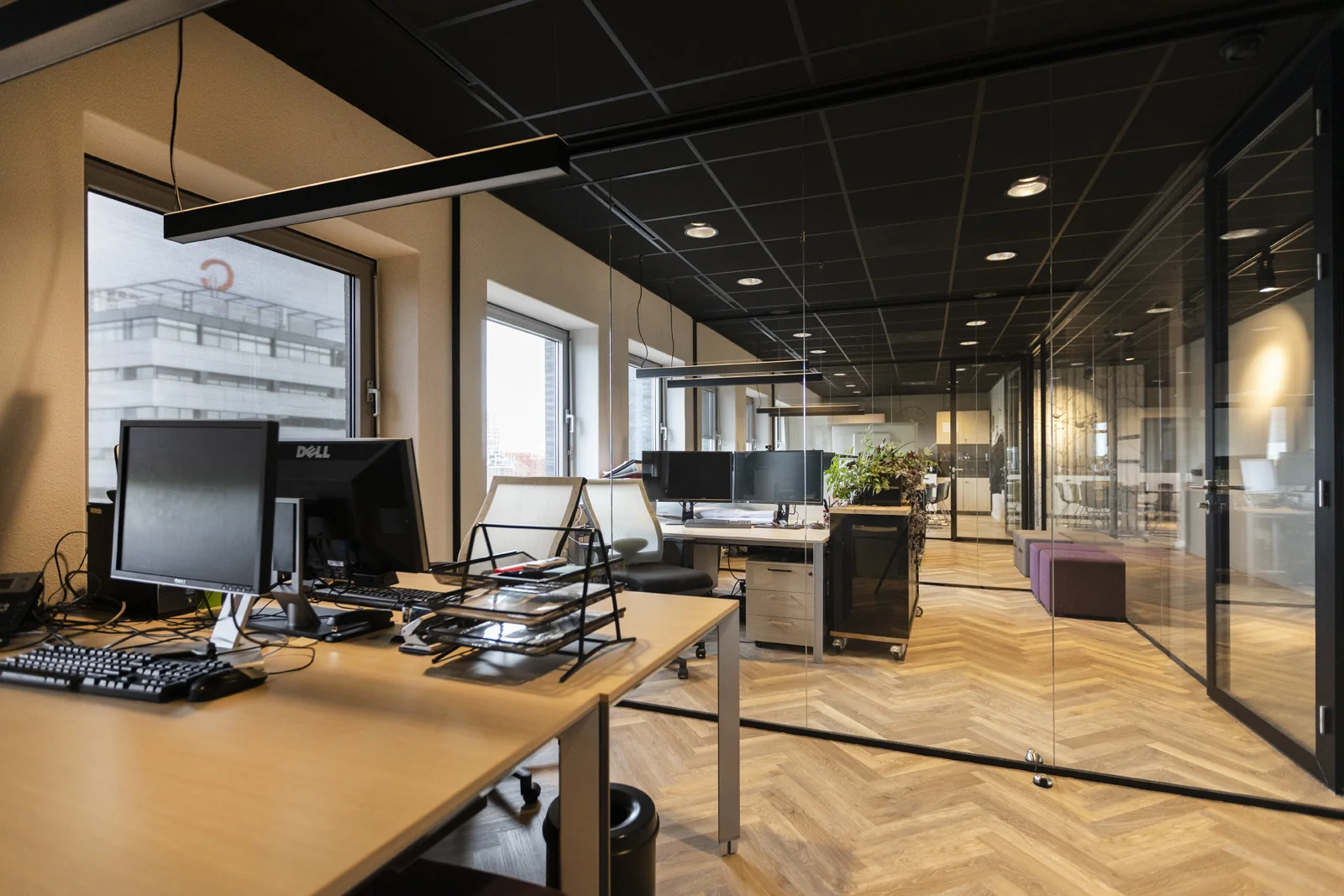 Moderne kantoorruimte in de Academie met werkplekken, computers en glazen wanden.