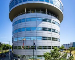 Ronde achtergevel van een modern kantoorgebouw met horizontale ramen en vlaggen.