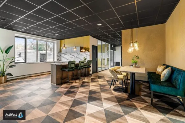 Moderne kantoorruimte in Agro Business Park 22 met stijlvolle zithoeken, een bar met barkrukken en opvallende geometrische vloer.