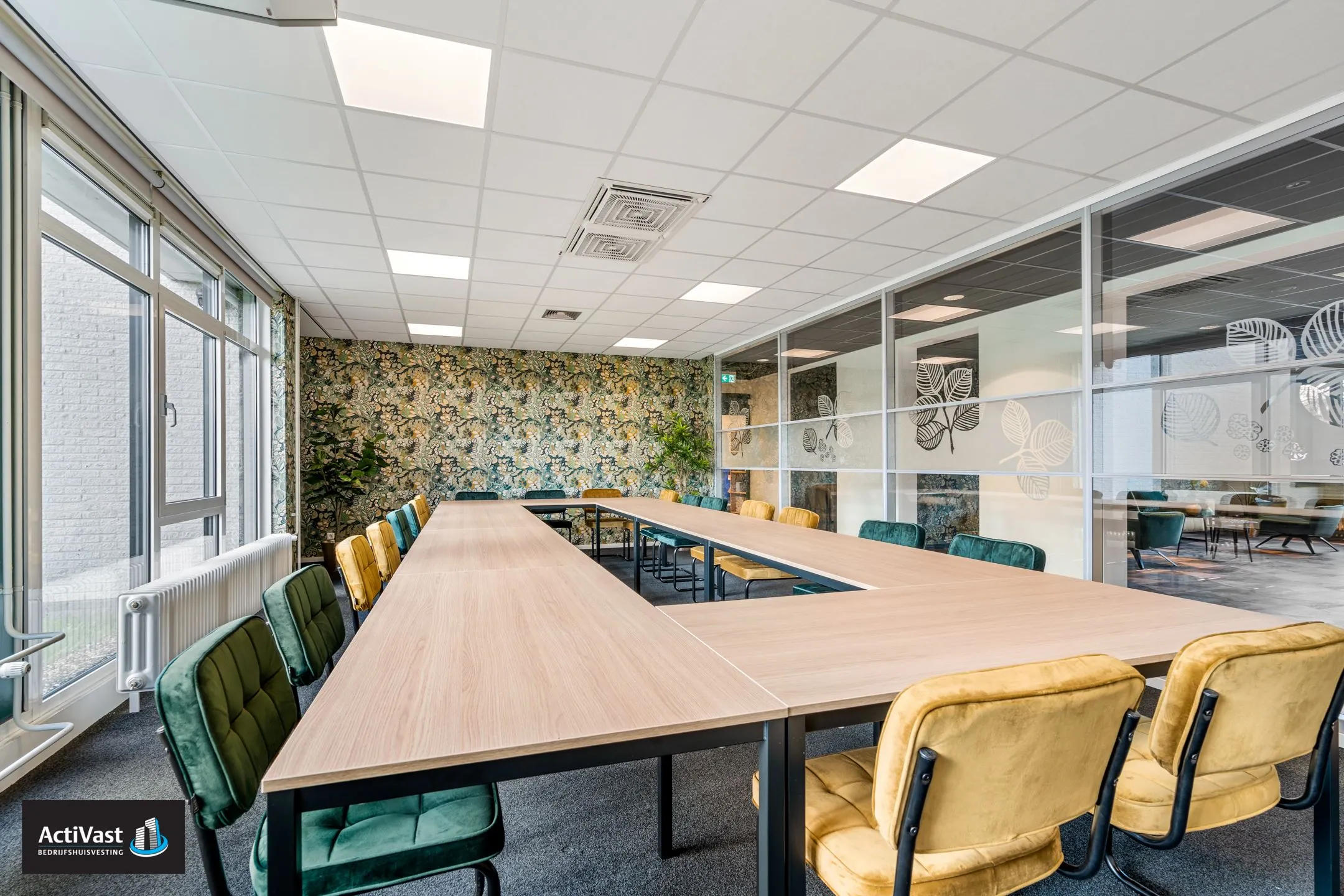 Vergaderruimte in Agro Business Park 22_11 met U-opstelling, kleurrijke stoelen en een decoratieve bloemenmuur.