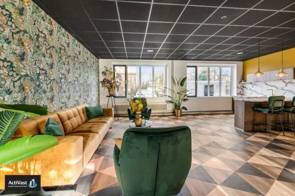 Stijlvol ingerichte lounge- en keukenruimte in Agro Business Park 22_6 met een bloemenbehang, fluwelen meubels en moderne afwerking.