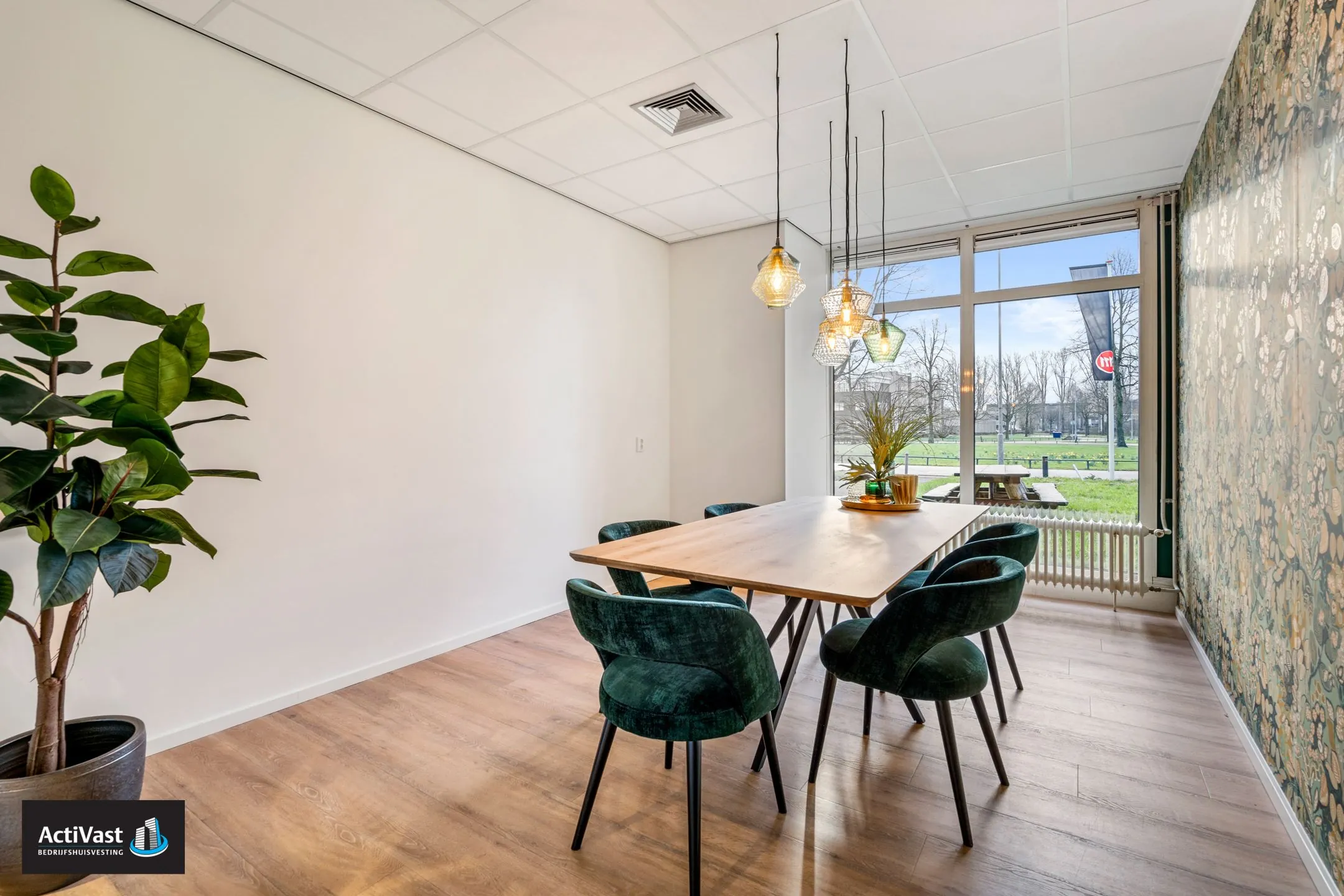 Vergaderruimte in Agro Business Park 22_9 met houten tafel, donkergroene stoelen, hanglampen en uitzicht op het grasveld buiten.