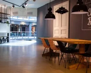 Moderne, open werk- of ontmoetingsruimte in Almere met een lange houten tafel, kleurrijke stoelen en industriële hanglampen.