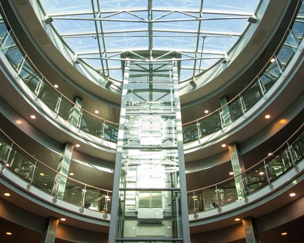 Moderne ronde binnenruimte in Almere met glazen lift en glazen koepeldak.