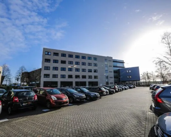 Kantoorgebouw AmsterdamAmersfoort-1645 met parkeerterrein vol auto's op een zonnige dag.