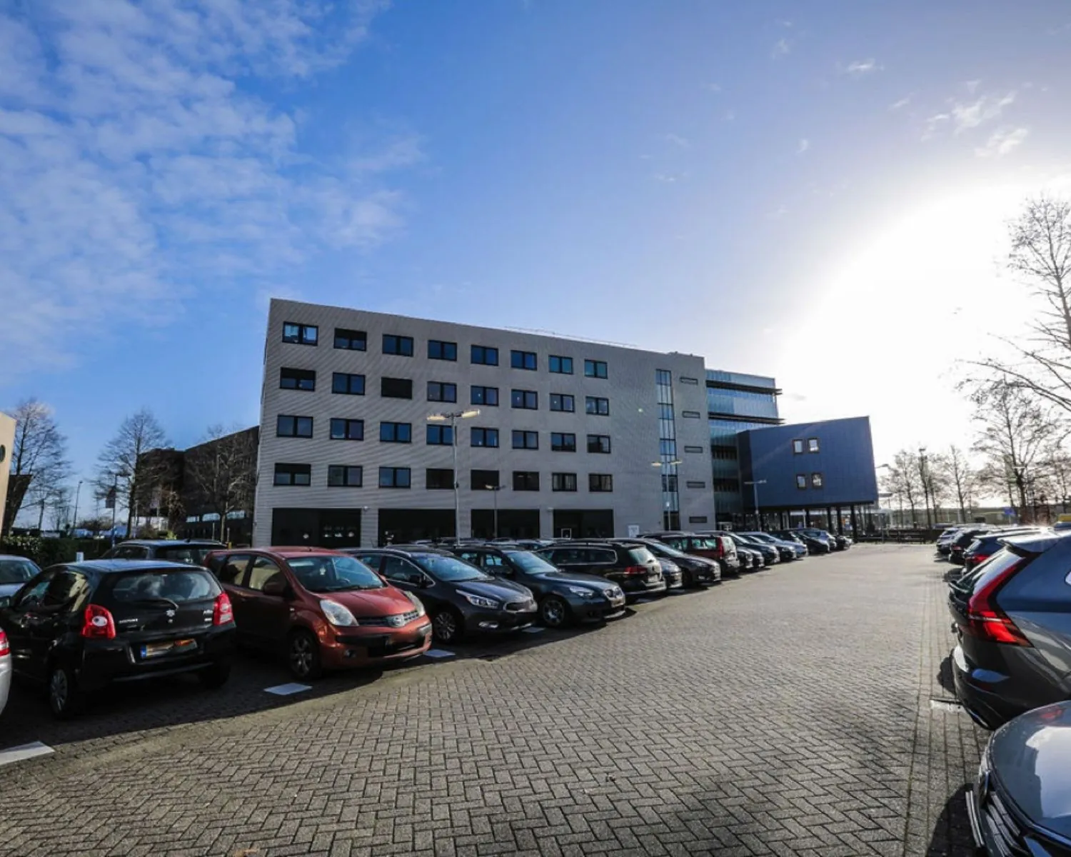 Kantoorgebouw AmsterdamAmersfoort-1645 met parkeerterrein vol auto's op een zonnige dag.