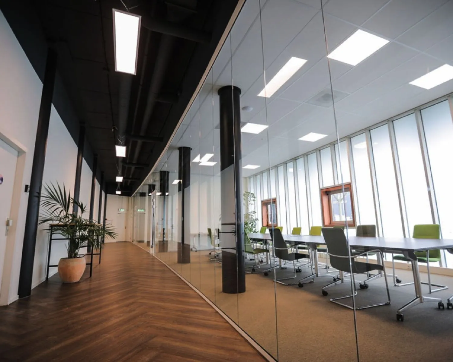 Moderne kantoorruimte met glazen vergaderruimte en houten visgraatvloer in Amsterdam-Amersfoort.