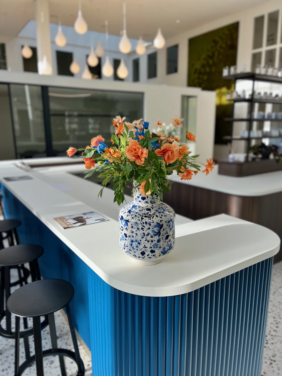 Bloemstuk in een Delfts blauwe vaas op een modern wit en blauw kookeiland in Lounge 0.10.