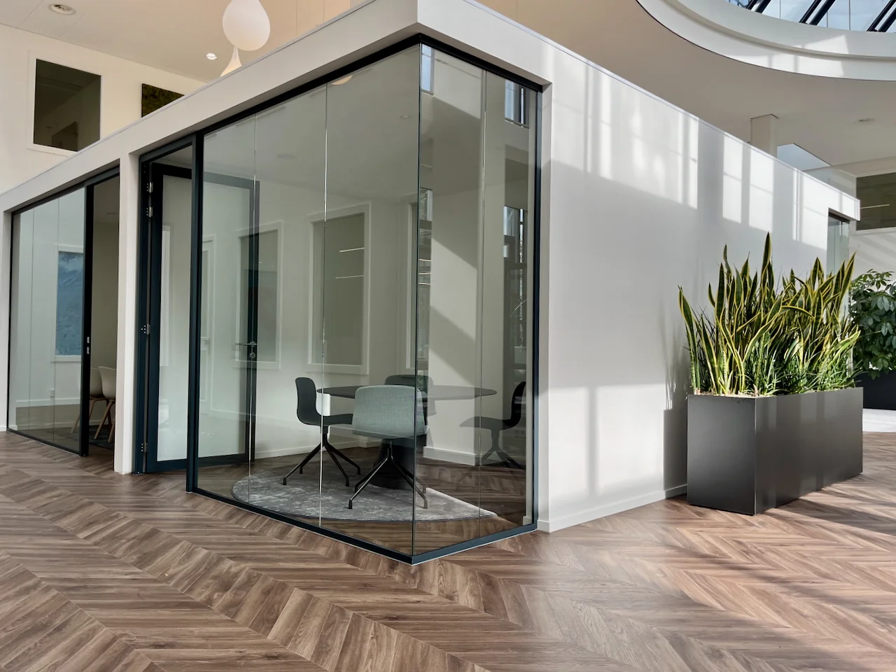 Glazen vergaderruimte Lounge 0.16 met moderne inrichting en planten in een lichte kantooromgeving.