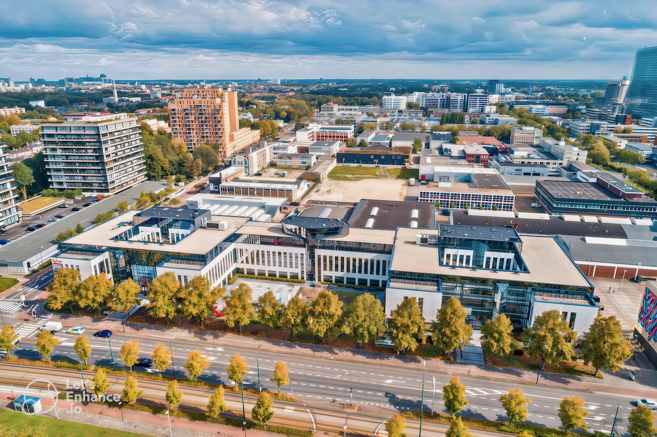 Luchtfoto van Gebouw 0.01 op de campus van de Technische Universiteit Eindhoven, omringd door wegen, bomen en omliggende gebouwen.