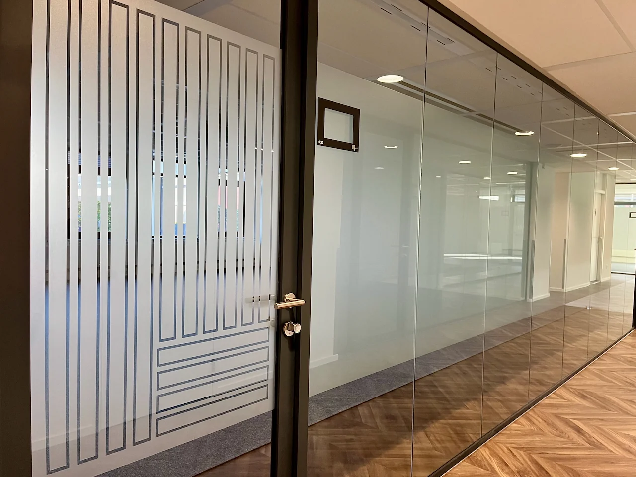 Moderne kantoorruimte met glazen wanden en een deur met matglazen strepen.