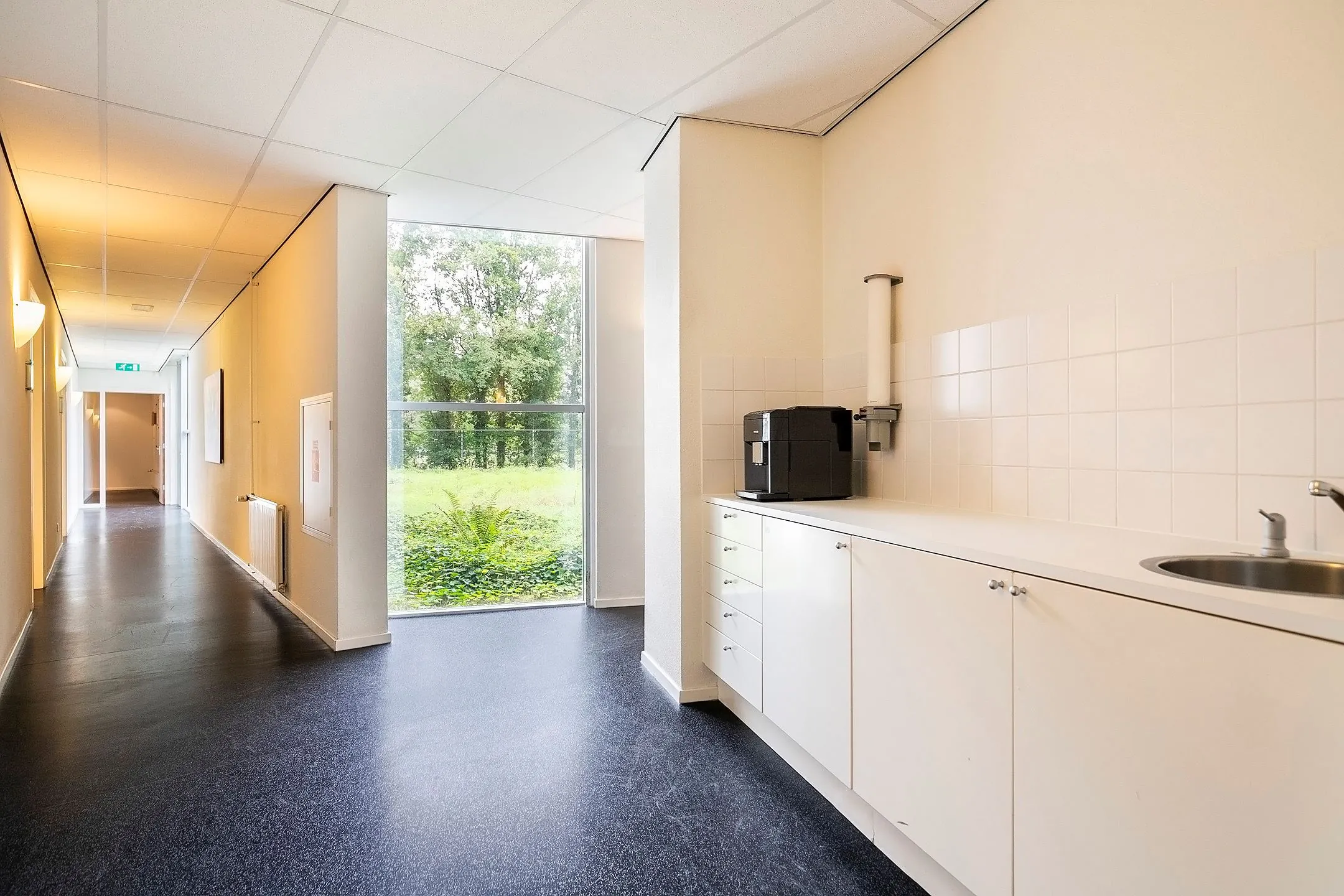 Keukenblok met koffiezetapparaat en spoelbak in een lichte gang van Banningstraat 3_9 met uitzicht op groen.