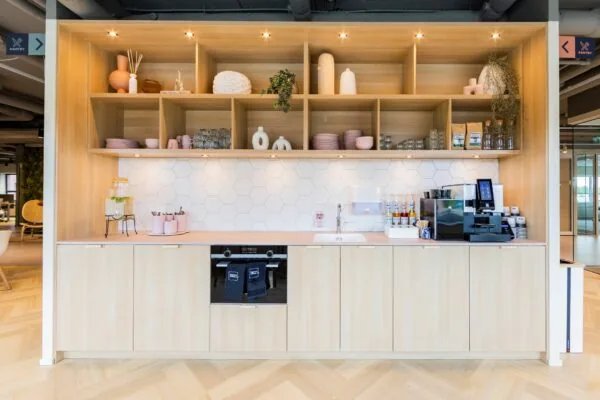 Moderne pantry met houten kasten, open planken, een koffiemachine en decoratieve accessoires aan de Baron van Nagellstraat 136.