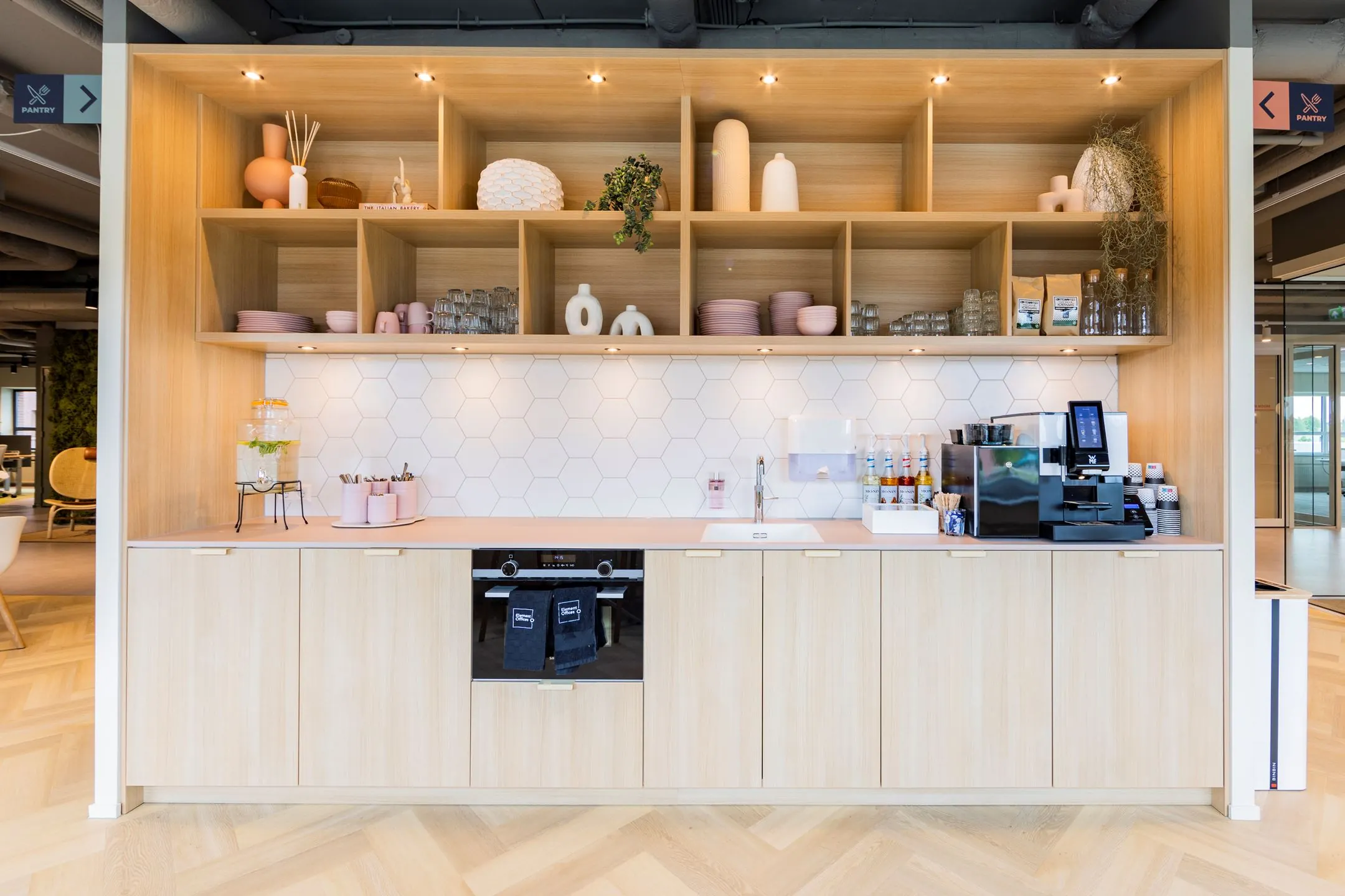 Moderne pantry met houten kasten, open planken, een koffiemachine en decoratieve accessoires aan de Baron van Nagellstraat 136.