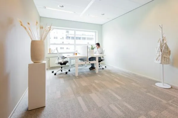 Modern en licht kantoor aan de Baron van Nagellstraat 136 met een persoon aan het werk achter een bureau.