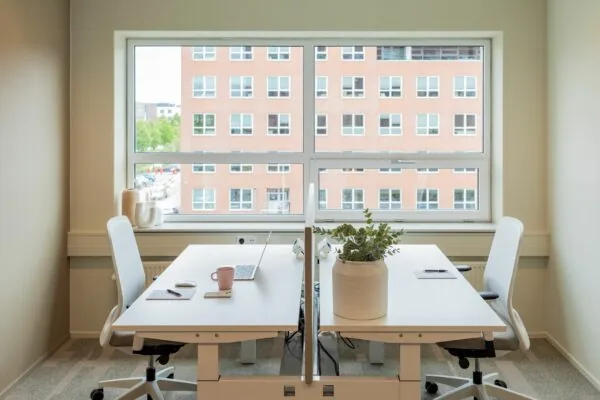 Modern kantoor met twee werkplekken aan een wit bureau bij het raam op Baron van Nagellstraat 136.