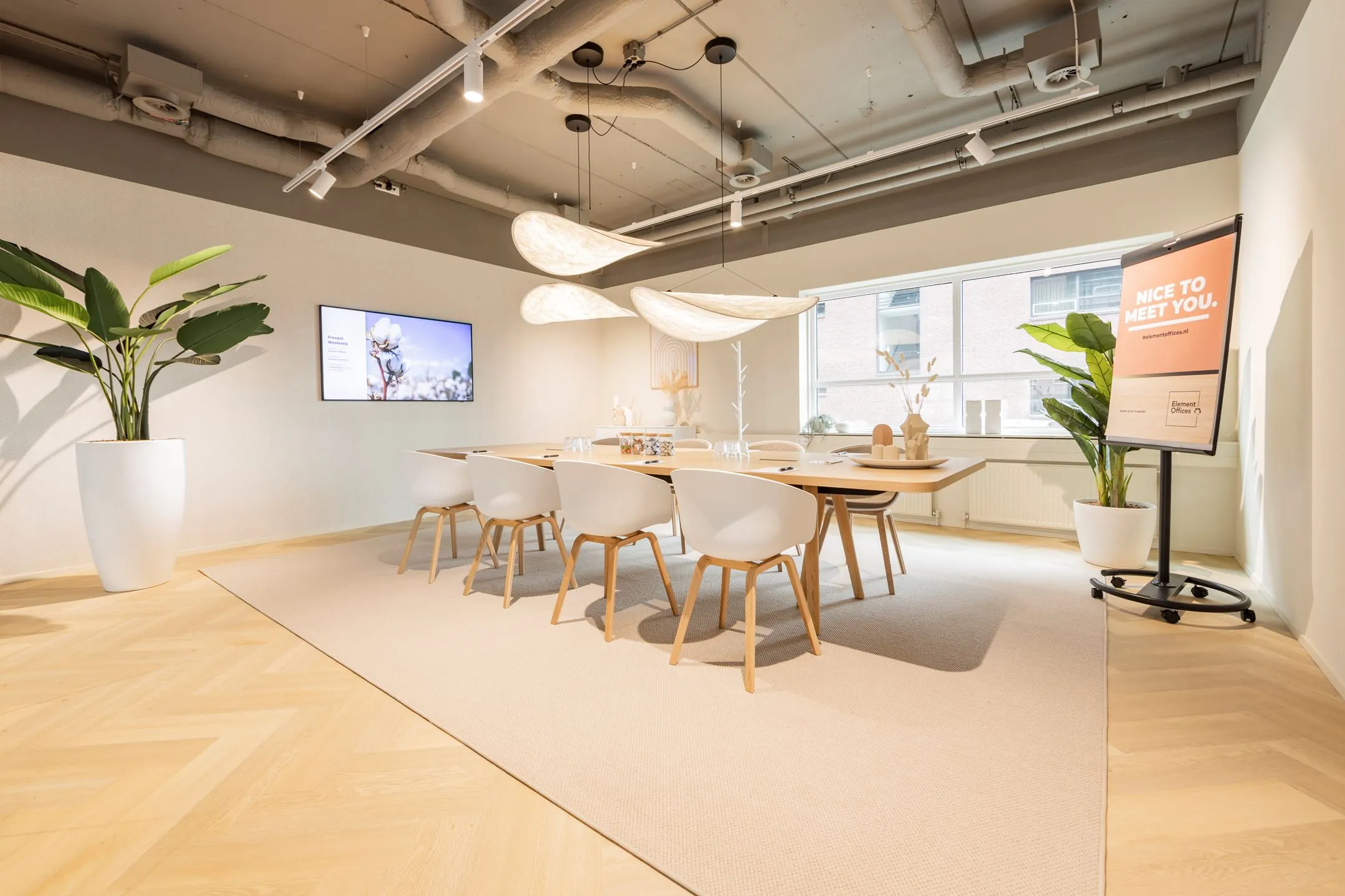 Moderne vergaderruimte aan de Baron van Nagellstraat 136 met een lange houten tafel, strakke witte stoelen en sfeervolle verlichting.