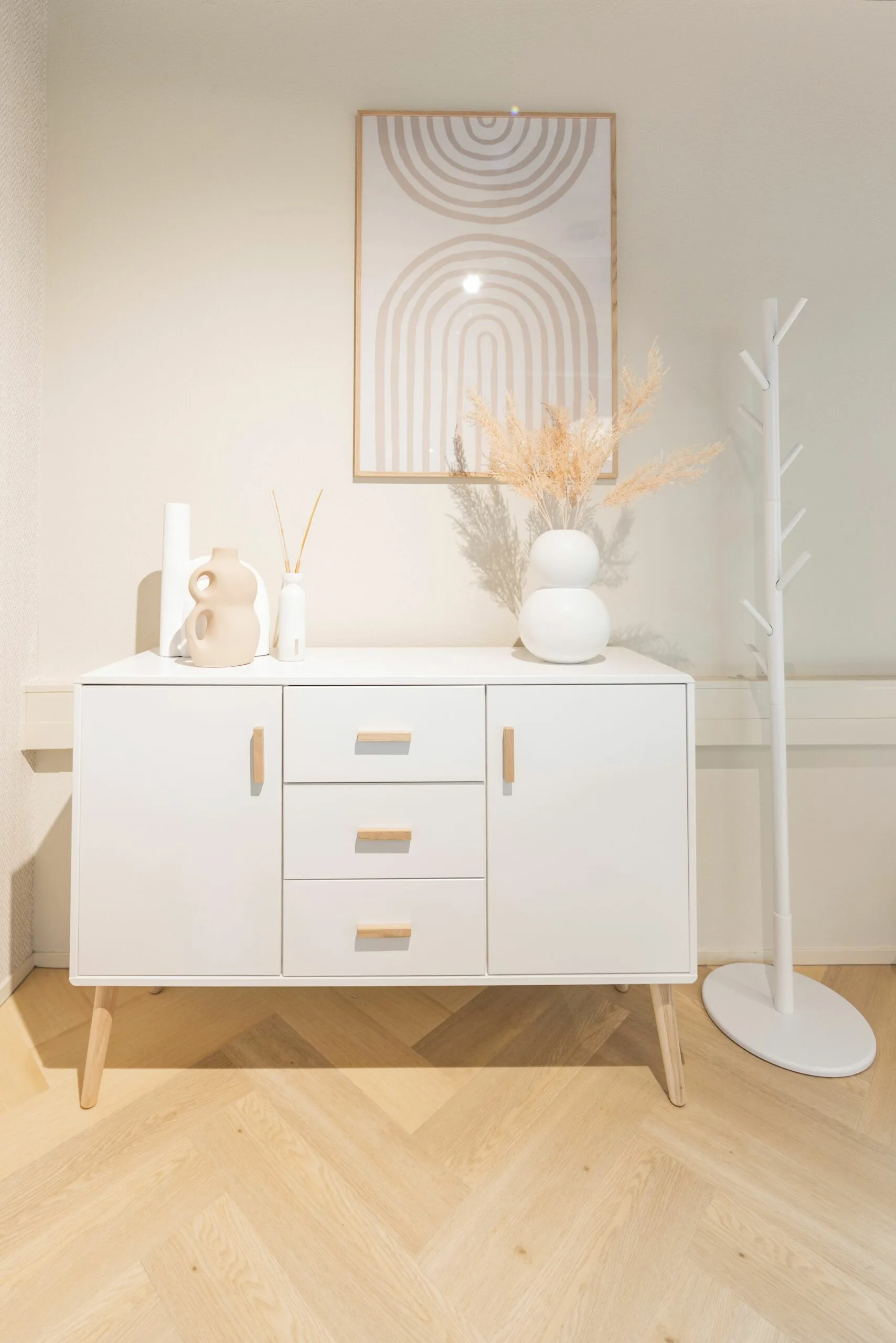 Wit dressoir met houten accenten, decoratieve vazen en wandkunst in een modern, minimalistisch interieur aan de Baron van Nagellstraat 136.