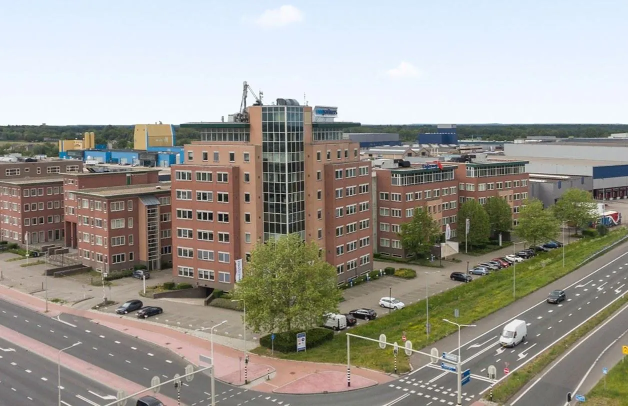 Kantoorgebouw aan de Baron van Nagellstraat 136 met meerdere verdiepingen, gelegen naast een drukke weg en omringd door industriële panden.