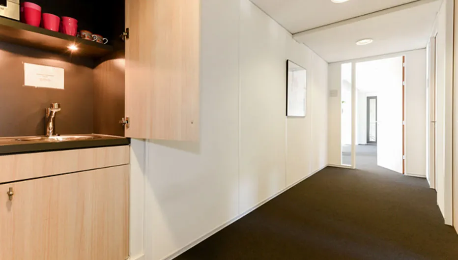 Lichte kantoorhal met een pantry en openstaande kastdeuren aan de Bezuidenhoutseweg 161.