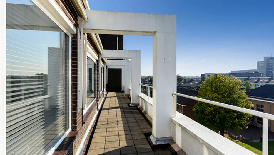 Balkon met witte balustrade en moderne overkapping aan Bezuidenhoutseweg 161 met uitzicht op de stad.