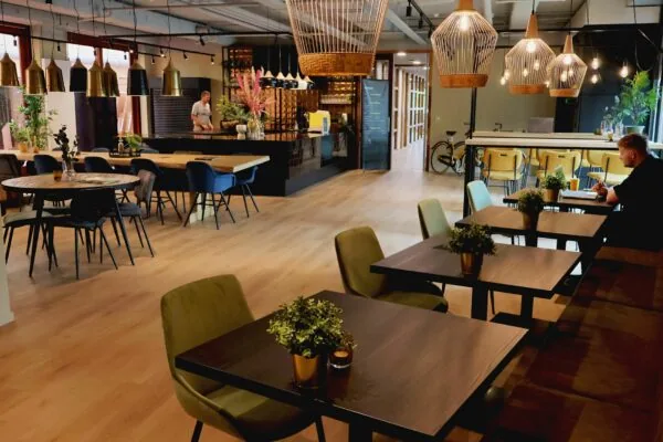 Moderne en sfeervolle ontmoetingsruimte in Blankenstein 400 met houten vloeren, diverse zitplekken, planten en designverlichting.