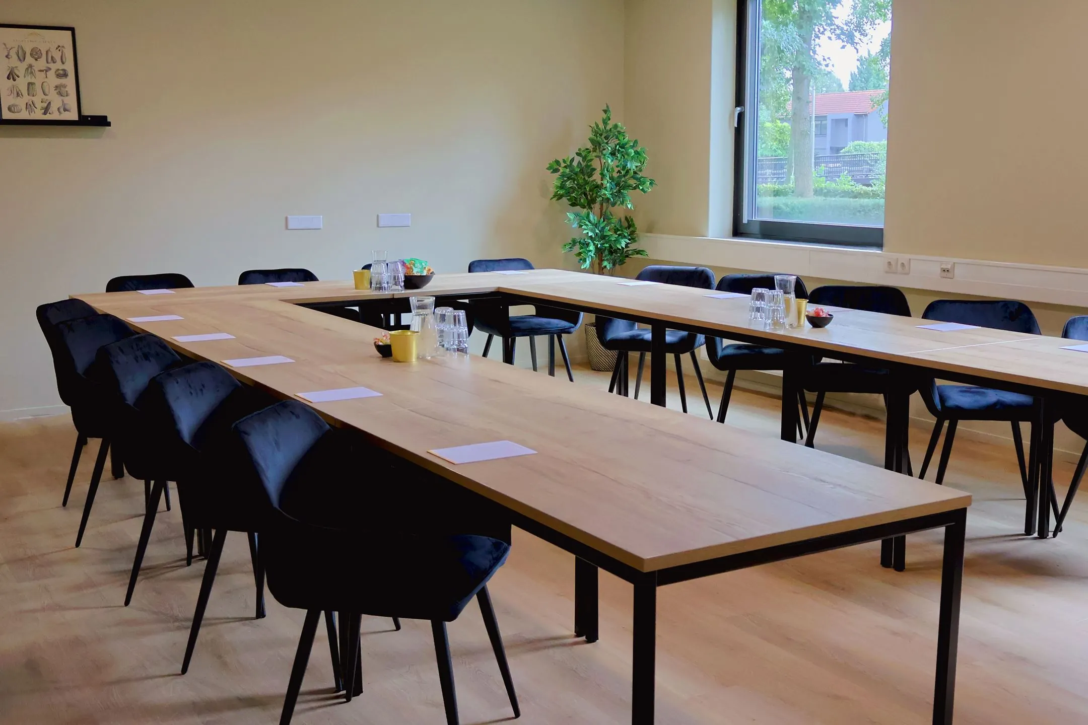 Vergaderruimte Blankenstein 400 met U-vormige opstelling, zwarte stoelen en schrijfmaterialen.