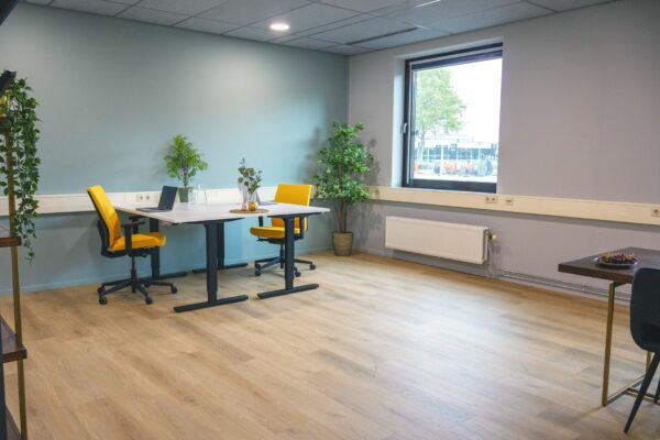 Modern ingerichte kantoorruimte in Blankenstein 400 met twee bureaus, gele stoelen en veel natuurlijk licht.