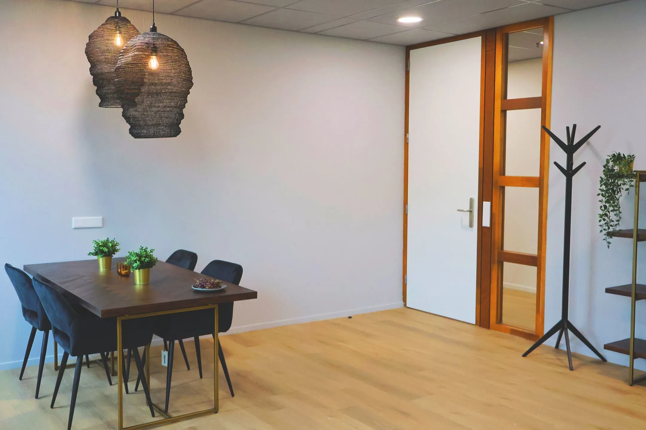 Moderne vergaderruimte bij Blankenstein 400 met houten tafel, zwarte stoelen, hanglampen en planten.