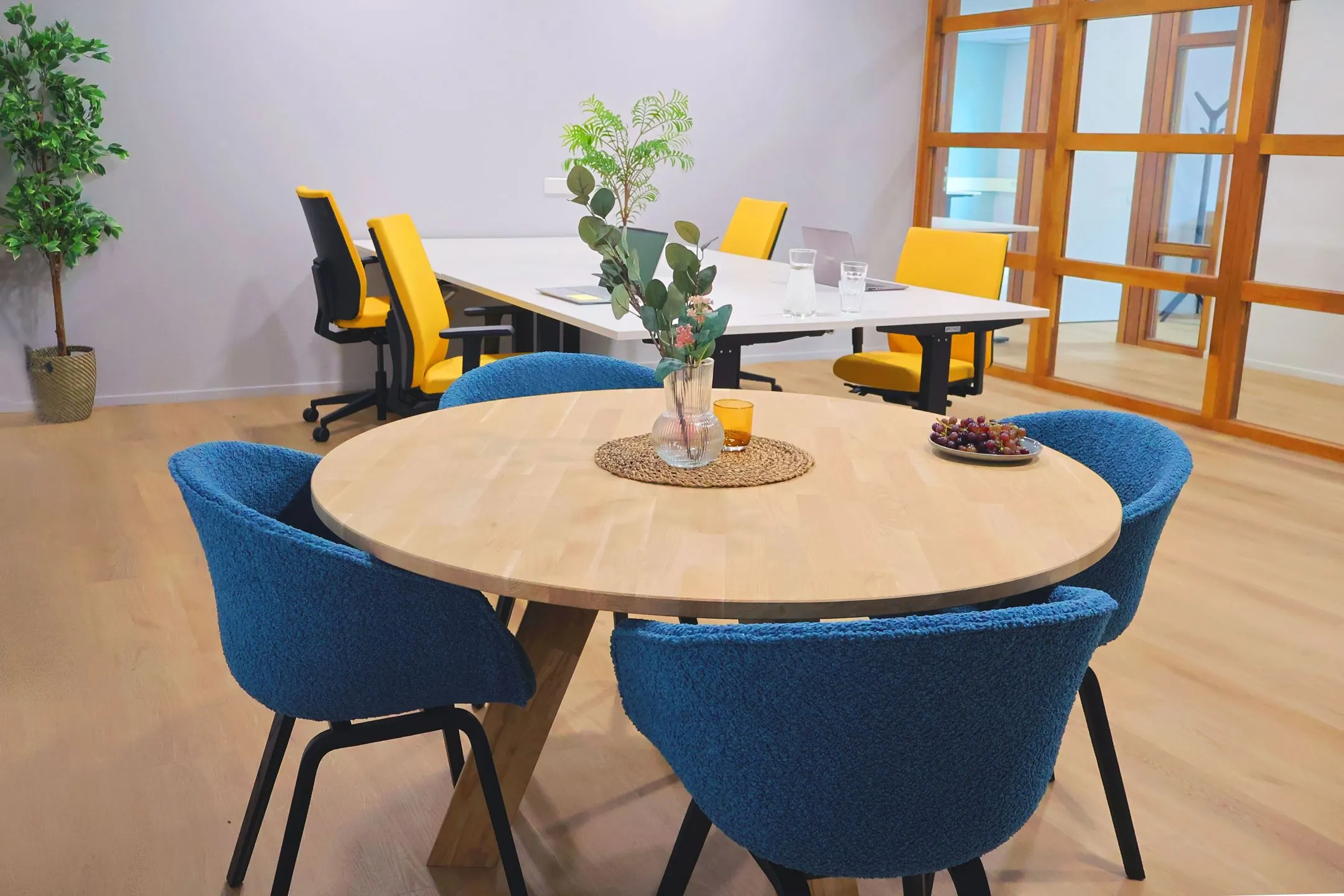 Moderne vergaderruimte in Blankenstein 400 met een ronde houten tafel, blauwe stoelen en geel-zwarte bureaustoelen.