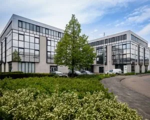 Modern kantoorgebouw aan de Cypressbaan 7-9 in Capelle aan den IJssel, omgeven door groen en geparkeerde voertuigen.