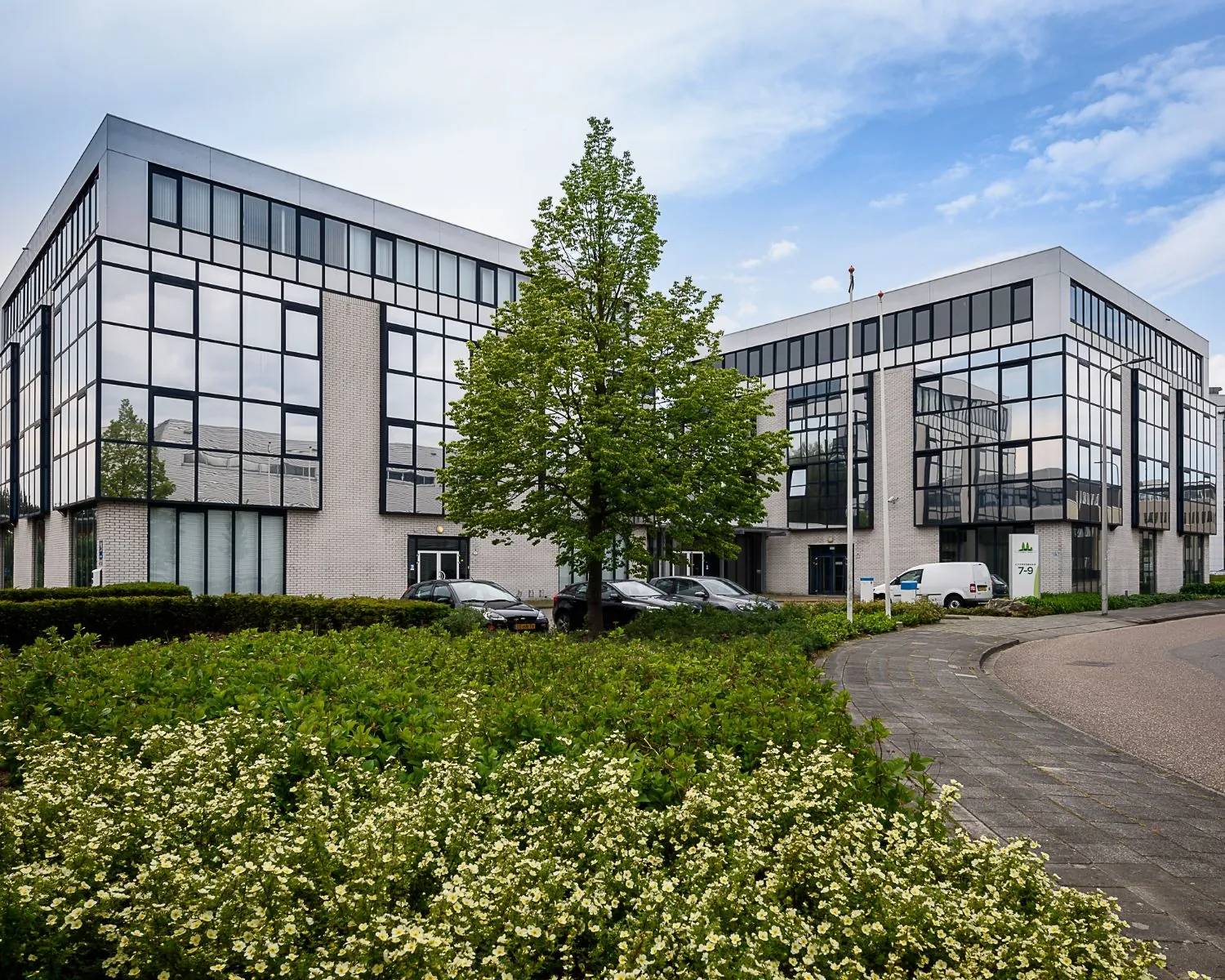 Modern kantoorgebouw aan de Cypressbaan 7-9 in Capelle aan den IJssel, omgeven door groen en geparkeerde voertuigen.