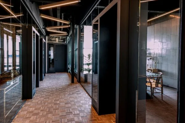 Moderne kantoorruimte aan Ceintuurbaan 28 met houten vloer, strakke zwarte details en glazen wanden.