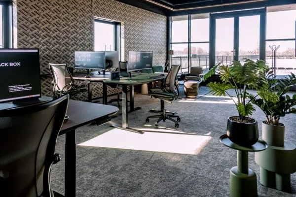 Modern kantoorinterieur op Ceintuurbaan 28 met bureaus, ergonomische stoelen, grote ramen en groene planten.