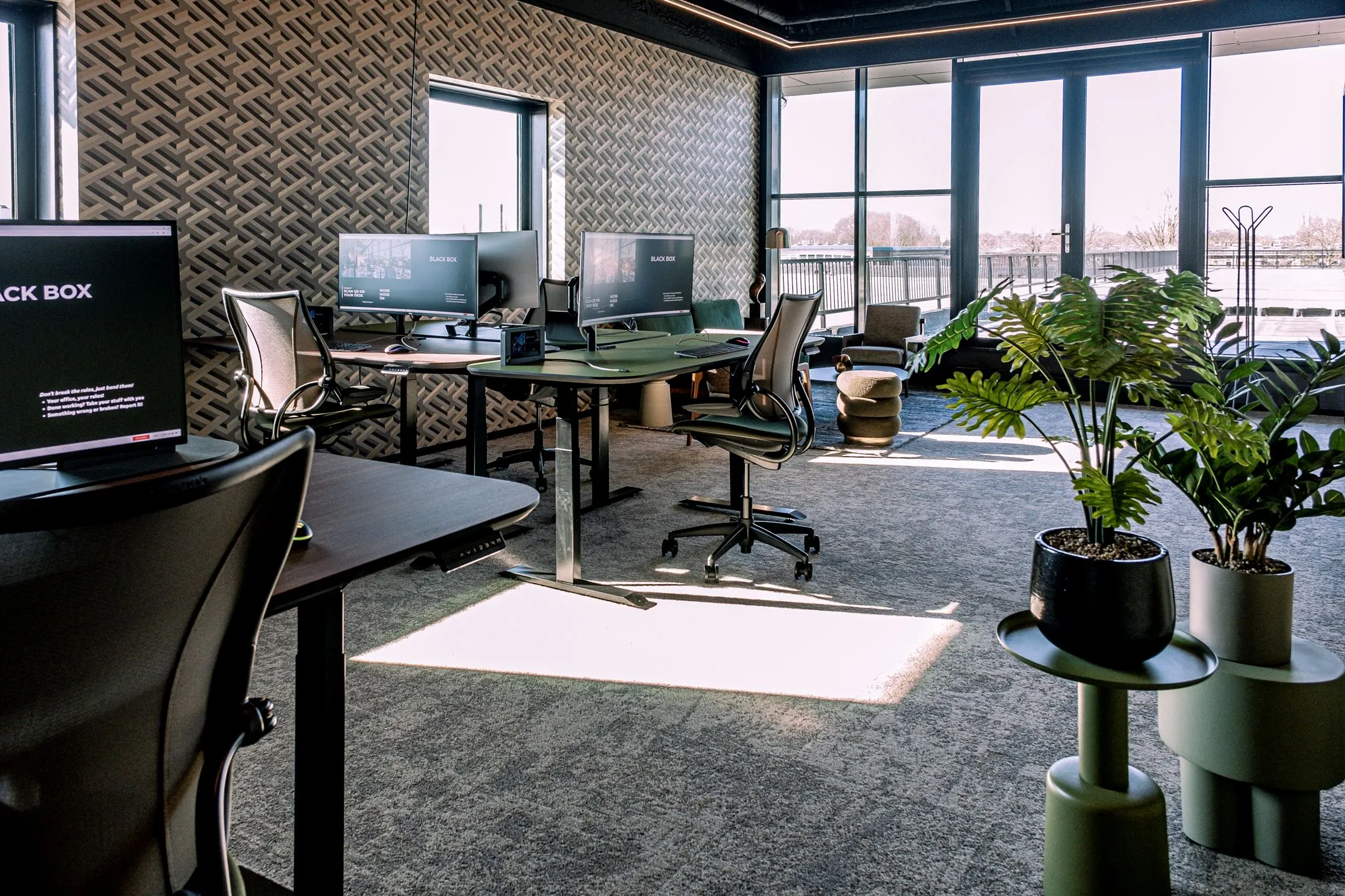 Modern kantoorinterieur op Ceintuurbaan 28 met bureaus, ergonomische stoelen, grote ramen en groene planten.