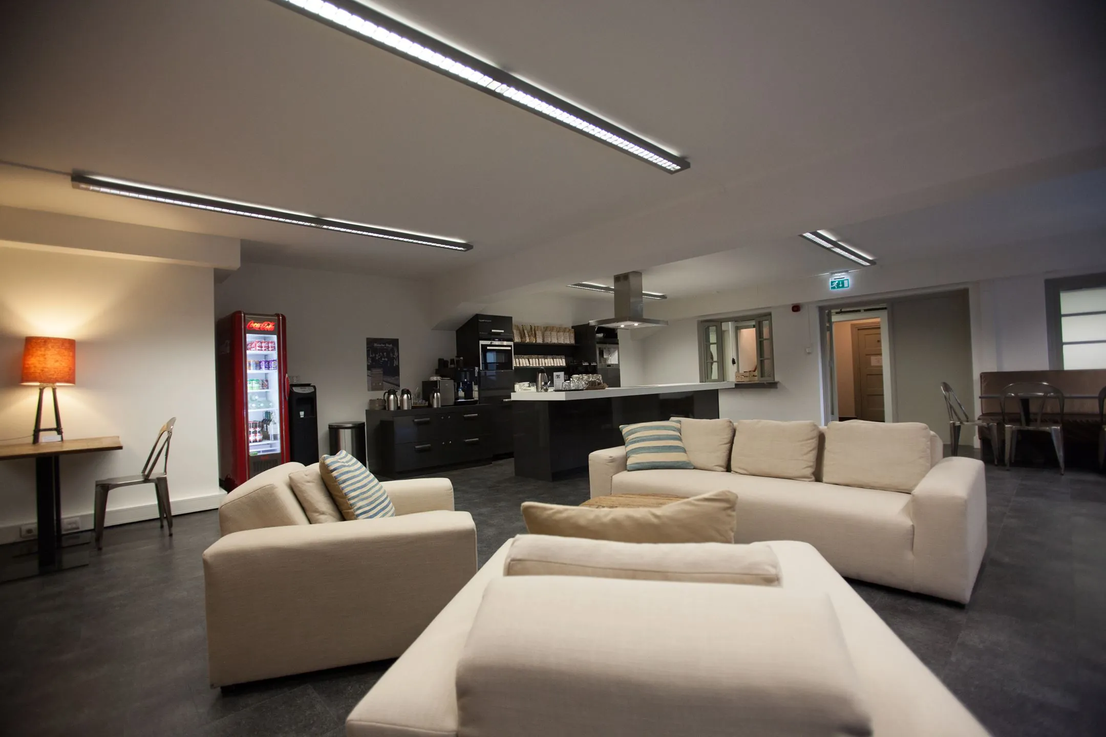 Moderne lounge- en keukenzaal met beige banken, een koffiehoek en een rode drankautomaat aan de Ceresstraat 13.