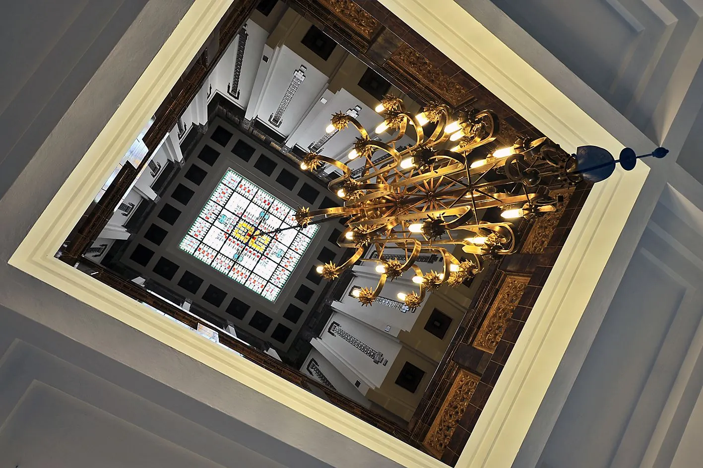Blik omhoog in het trappenhuis van Ceresstraat 13 met een grote sierlijke kroonluchter en glas-in-lood plafond.