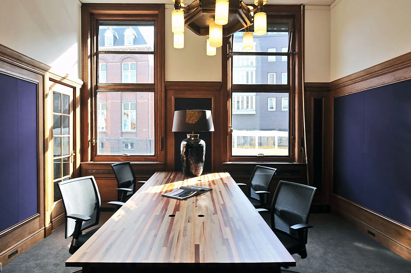 Vergaderruimte aan de Ceresstraat 13 met houten tafel, zes bureaustoelen, hoge ramen en klassieke houten afwerking.