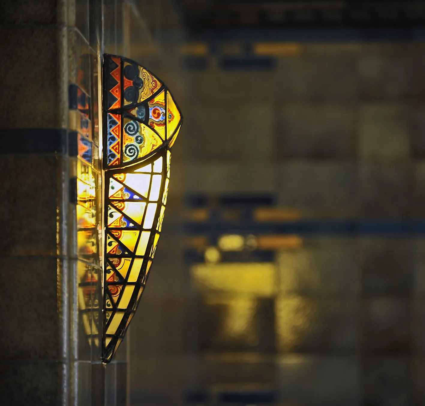 Decoratieve wandlamp van glas-in-lood in art-decostijl aan een betegelde muur in Ceresstraat 13.