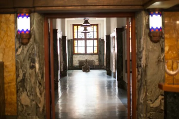 Marmeren gang in het gebouw aan de Ceresstraat 13 met een beeld en glas-in-loodraam aan het einde.